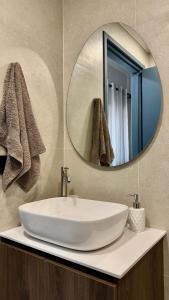 a bathroom sink with a round mirror above it at Melintas cozy apartments 2 in Plomari +14 photos