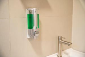 a green and silver soap dispenser on a bathroom wall at Ecobox in Santa Rosa +30 photos