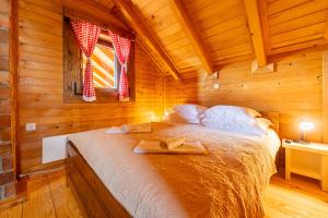 a bedroom with a bed in a wooden cabin at Log Cabin Valley - Private Villa with Pool in Gospić
