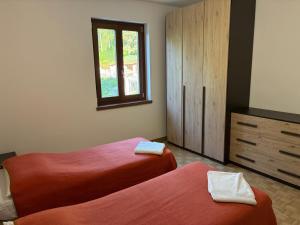 a bedroom with two beds and a dresser and a window at Casa RIGPA in Bellagio