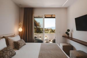 a bedroom with a white bed and a large window at Ammolofos Luxury Apartment & suites in Naxos Chora