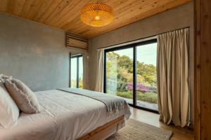 a bedroom with a bed and a large window at Casa da Figueira in São Roque do Pico +35 photos