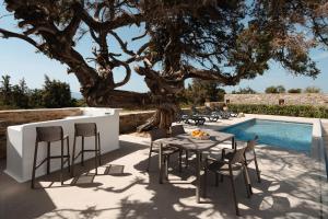 a patio with a table and chairs next to a tree at Ammolofos Luxury Apartment & suites in Naxos Chora