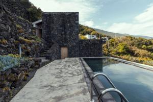 a house with a swimming pool and a stone wall at Casa da Figueira in São Roque do Pico