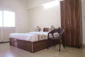 a bedroom with a bed and a chair in it at Sri Darshini Comfort Hinkal Mysore in Vānivilāsa Puram