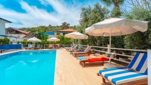 a swimming pool with lounge chairs and umbrellas next to a pool at Flower Apart 2 - Flower Hotel Patara in Gelemiş