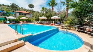 a pool with chairs and umbrellas at a resort at Flower Apart 2 - Flower Hotel Patara in Gelemiş