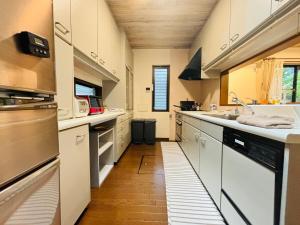 a large kitchen with white cabinets and a wooden floor at Sakai Garden and Villa in Sakai