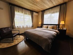 a bedroom with a large bed and a chair at Sakai Garden and Villa in Sakai
