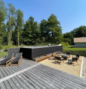 a wooden deck with chairs and a table on top at Ecrin de Vizaille in Toucy