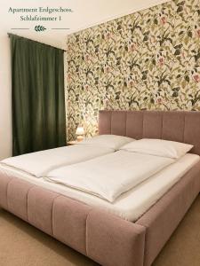 a large bed in a bedroom with a floral wallpaper at Villa Deli in Wischhafen