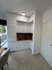a kitchen with white walls and a table and chairs at Sea Sand Apartment in Bijela Glavica