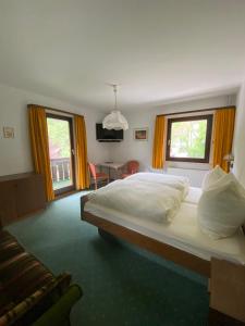a bedroom with a large bed and two windows at Ferienwohnungen in Schönmünzach in Baiersbronn