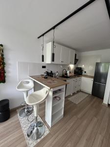 a kitchen with white cabinets and a counter with stools at Apartament Drzymały in Lubin