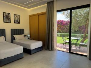 a bedroom with two beds and a patio with a table at Villa Zahi in El Aïn +107 photos