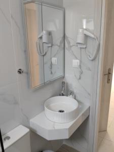 a white bathroom with a sink and a mirror at Apartments Gregory & George in Hanioti +60 photos