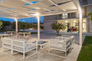 a patio with white chairs and tables and a building at Netum Hotel in Noto