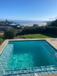 a swimming pool with the ocean in the background at Sea and Sky Rooiels in Rooiels