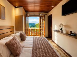 a bedroom with a bed and a large window at Flats Morada do Jordão in Campos do Jordão