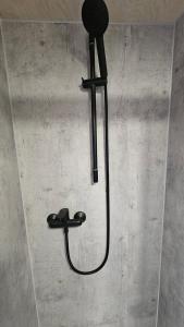 a shower with a black shower head on a wall at Glamping Šumava in Hartmanice