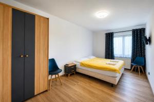 a bedroom with a bed and two blue chairs at Apartament pod gruszą in Legbąd