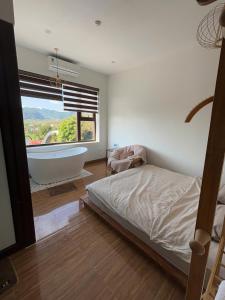 a bedroom with a bed and a tub and a window at Lơ Mơ House in Làng Môn +13 photos