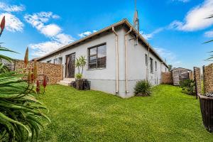 a white house with a grass yard in front of it at Swallows Nest Haven in Boksburg