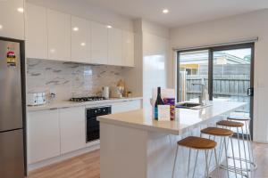 a kitchen with white cabinets and a counter with stools at Shell Escape at Ocean Grove in Ocean Grove