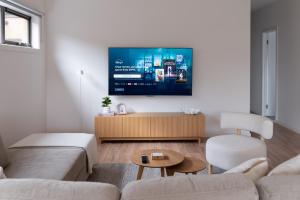 a living room with a couch and a tv on a wall at Shell Escape at Ocean Grove in Ocean Grove