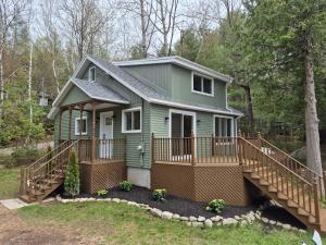 a green tiny house with a large deck at Chalet lac Chantelle in Chertsey