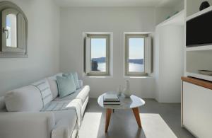 a white living room with a white couch and a table at Grace Hotel, Auberge Collection in Imerovigli