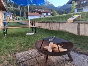 a picnic table with a grill and an umbrella at Hochtal Apartments in Tannheim