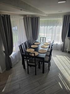 a dining room with a table and chairs and curtains at D&A Vila - Private Villa with Sauna & Hot Tub in Arciūnai