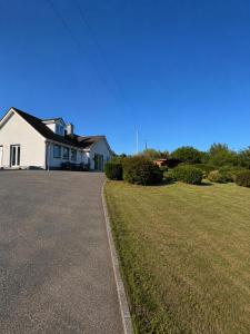 a white house with a grassy yard in front of it at Tullyally House in Castle Cary