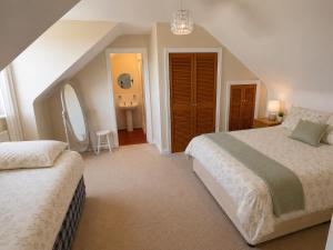 a attic bedroom with two beds and a bathroom at Tullyally House in Castle Cary