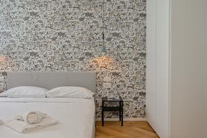a bedroom with a white bed with a brick wall at Palazzo Machiavelli Trieste in Trieste