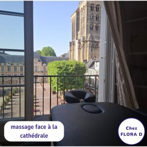 a room with a table and a balcony with a view of a building at Chez FLORA D - Lisieux hypercentre - in Lisieux +6 photos