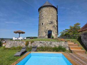 a pool in front of a tower with two chairs at Le Moulin de la Motte Baudoin in Noyers-sur-Cher