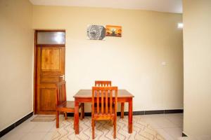 a dining room with a wooden table and two chairs at Daf House in Zanzibar City +2 photos