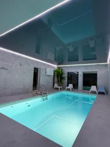 a large swimming pool with blue water in a building at La Park Aparthotel in Kudowa-Zdrój
