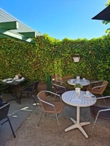 a patio with tables and chairs in front of a hedge at Hotel Haus Wittwer in Emden
