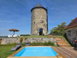 a building with a swimming pool next to a tower at Le Moulin de la Motte Baudoin in Noyers-sur-Cher