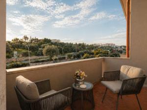 a balcony with two chairs and a table and a window at Aia del vento in Cisternino