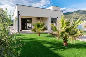 a white house with palm trees in the yard at Villa Elysian Blagaj in Blagaj