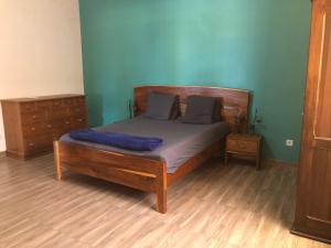 a bedroom with a bed with blue walls and wooden floors at Chez Roseline in Ndangane