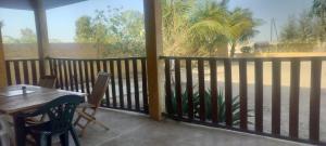 a porch with a wooden table and chairs and a window at Chez Roseline in Ndangane
