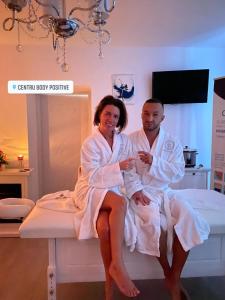 a man and a woman sitting on a bed at Apartamente Cugir in Cugir
