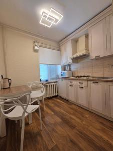 a kitchen with white cabinets and a table and chairs at Апартаменты в центре in Chernihiv