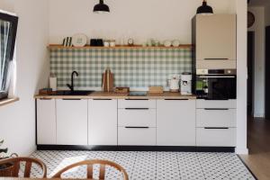 a kitchen with white cabinets and a refrigerator at Apartamenty Wrzosowa 23 z garażem na rowery in Kudowa-Zdrój