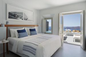 a white bedroom with a large bed and a balcony at Grace Hotel, Auberge Collection in Imerovigli +76 photos